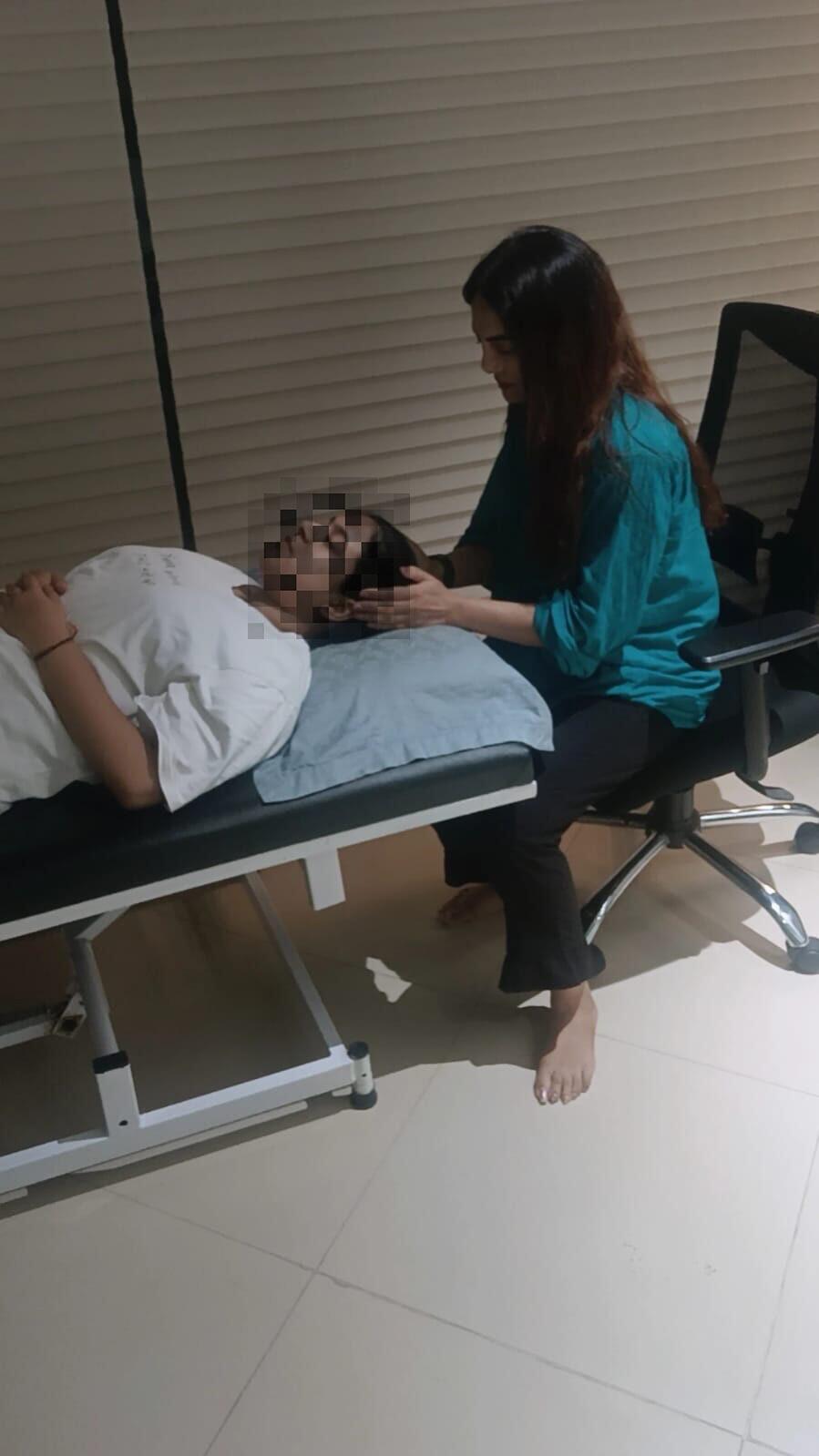 Vibha Jain seated beside a reclining client during a hypnotherapy session in a quiet room.