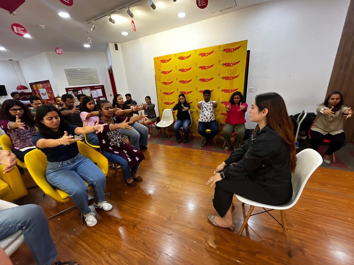 A wide view of a group session with participants seated in a semicircle following a guided exercise.
